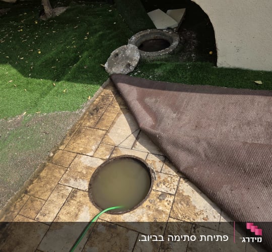 שאיבת מים ופתיחת סתימה בשוחת ביוב בחצר באמצעות צינור